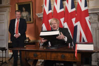 UK chief trade negotiator David Frost looks on as Britain's Prime Minister Boris Johnson signs the EU-UK Trade and Cooperation Agreement at 10 Downing Street, London Wednesday Dec. 30, 2020. The U.K. left the EU almost a year ago, but remained within the bloc’s economic embrace during a transition period that ends at midnight Brussels time —- 11 p.m. in London — on Thursday. European Commission President Ursula von der Leyen and European Council President Charles Michel signed the agreement during a brief ceremony in Brussels on Wednesday morning then the documents were flown by Royal Air Force plane to London for Johnson to add his signature. (Leon Neal/Pool via AP)