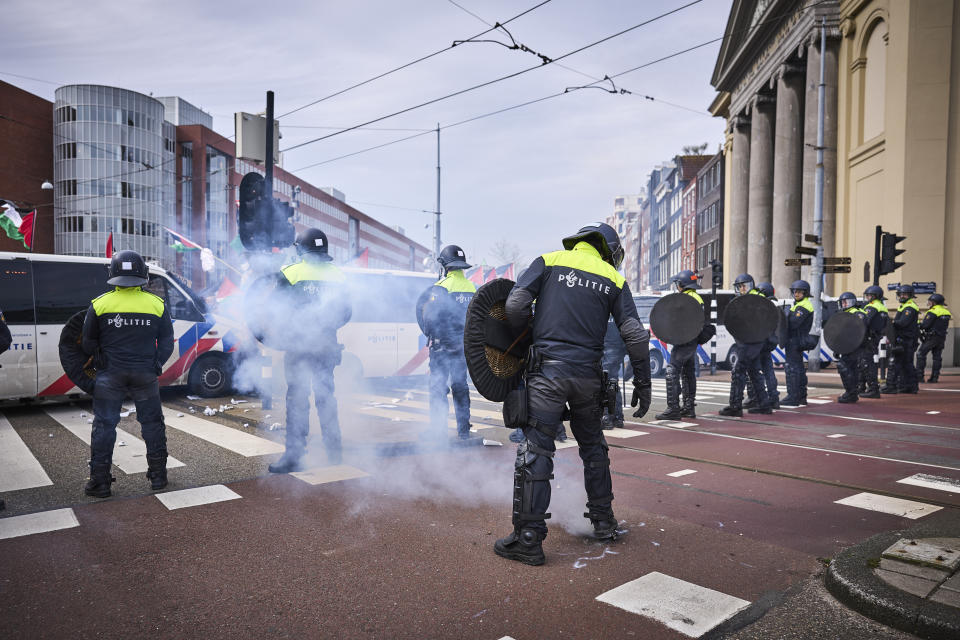 Demonstrators set off some firecrackers as Dutch riot police forms a line during a protest against Israel's President Isaac Herzog attending the opening of the new National Holocaust Museum in Amsterdam, Netherlands, Sunday, March 10, 2024. (AP Photo/Phil Nijhuis)