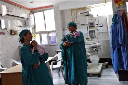 Rekha Patel, 42 (R), from Britain, holds her week-old-baby girl Gabriella, as she stands next to a doctor at the Akanksha IVF centre in Anand town, about 70 km (44 miles) south of the western Indian city of Ahmedabad August 25, 2013. REUTERS/Mansi Thapliyal