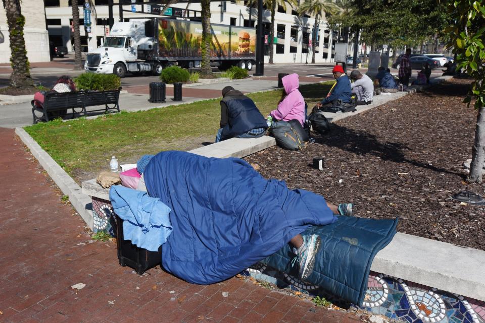 People with no homes find somewhere to stay during the day at a small park on Main Street across from the downtown main library in Jacksonville.