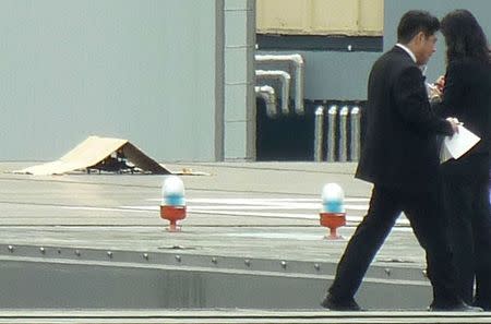 Police and security officers investigate near an unidentified drone (covered under a cardboard) which was found on the rooftop of Prime Minister Shinzo Abe's official residence in Tokyo, in this photo taken by Kyodo April 22, 2015. REUTERS/Kyodo