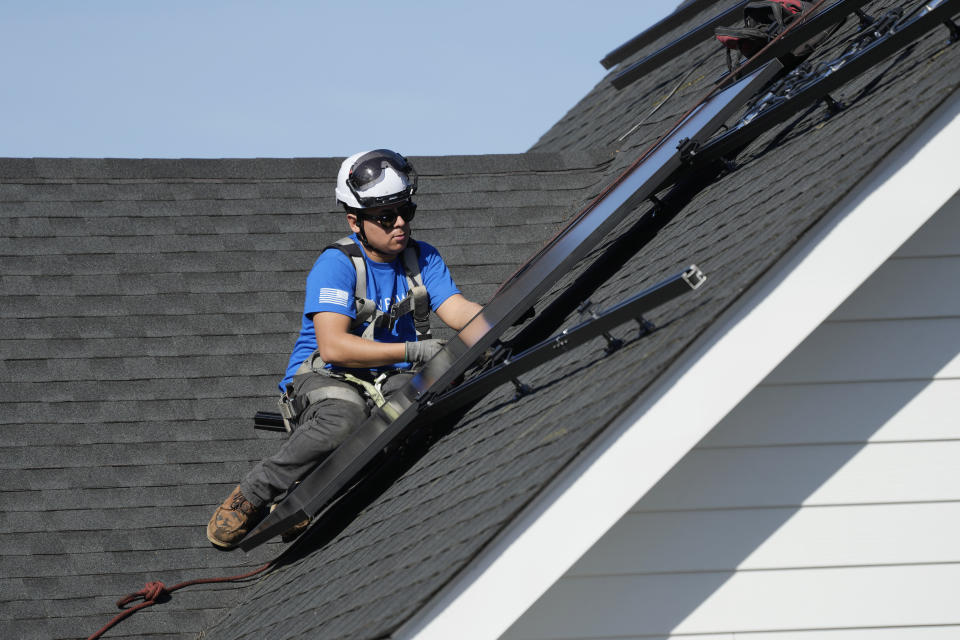 A solar panels technician works to install solar panels onto the roof of a home in Arlington Heights, Ill., Monday, Feb. 26, 2024. Record warmth is expected today and Tuesday. All time February highest temperature records could also be tied or broken in Illinois. (AP Photo/Nam Y. Huh)