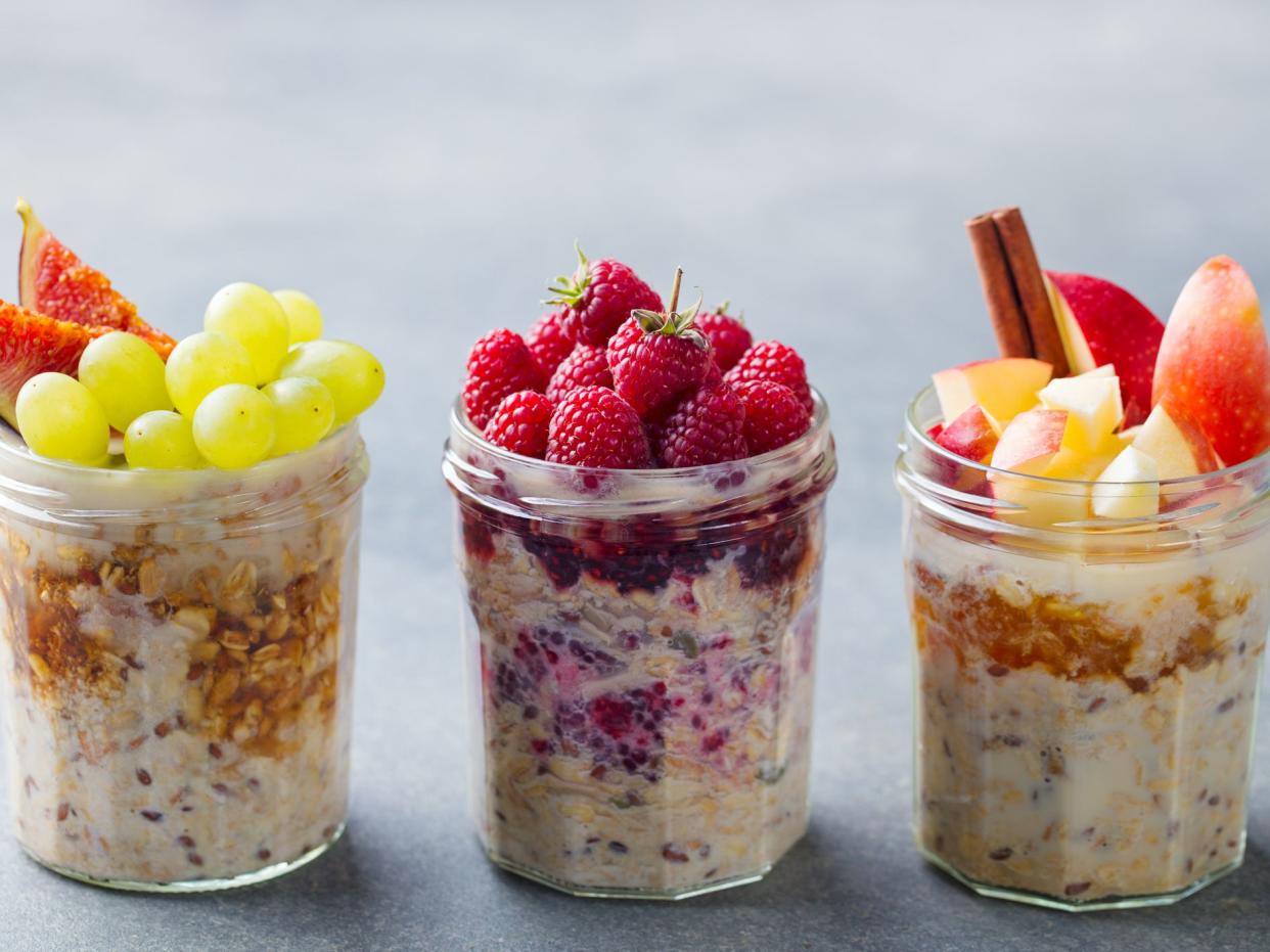 Assortment overnight oats, bircher muesli with fresh berries and fruits in a glass jars. Grey background.