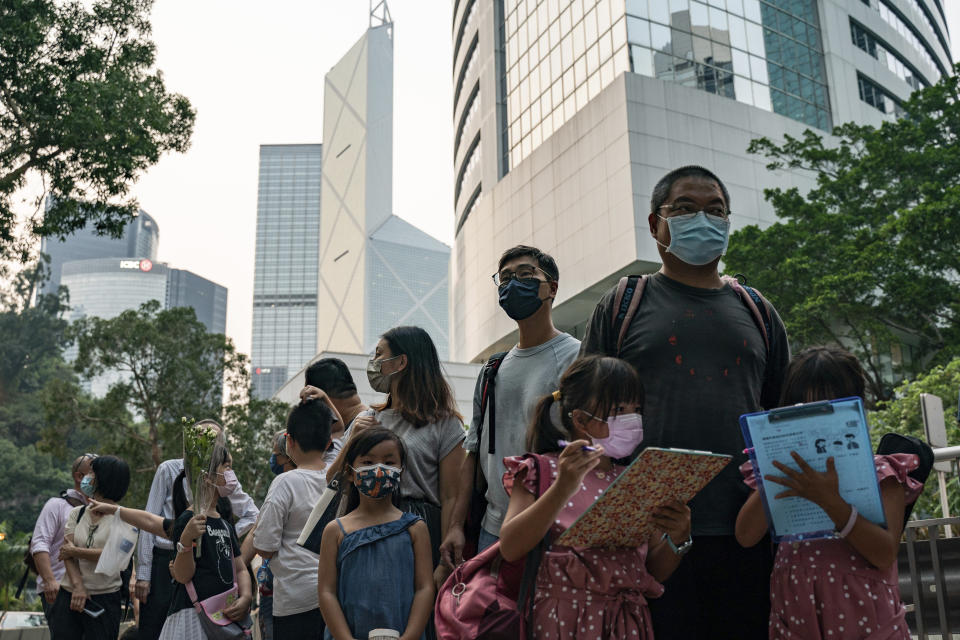 People wait in line to pay tribute to Queen Elizabeth II outside the British Consulate in Hong Kong, Friday, Sept. 16, 2022. Hundreds of Hong Kong residents are lining up in front of the British Consulate General for hours each day to pay their respects to Queen Elizabeth II, leaving piles of flowers and handwritten notes. (AP Photo/Anthony Kwan)