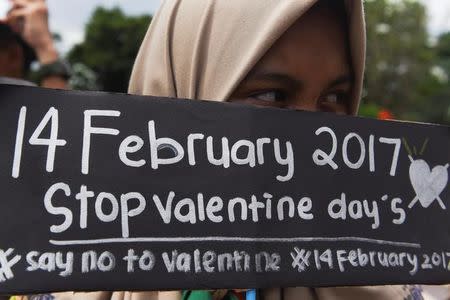 A Muslim student holds a poster during a protest against Valentine's Day celebrations in Surabaya, Indonesia, February 13, 2017 in this photo taken by Antara Foto. Antara Foto/Zabur Karuru/ via REUTERS