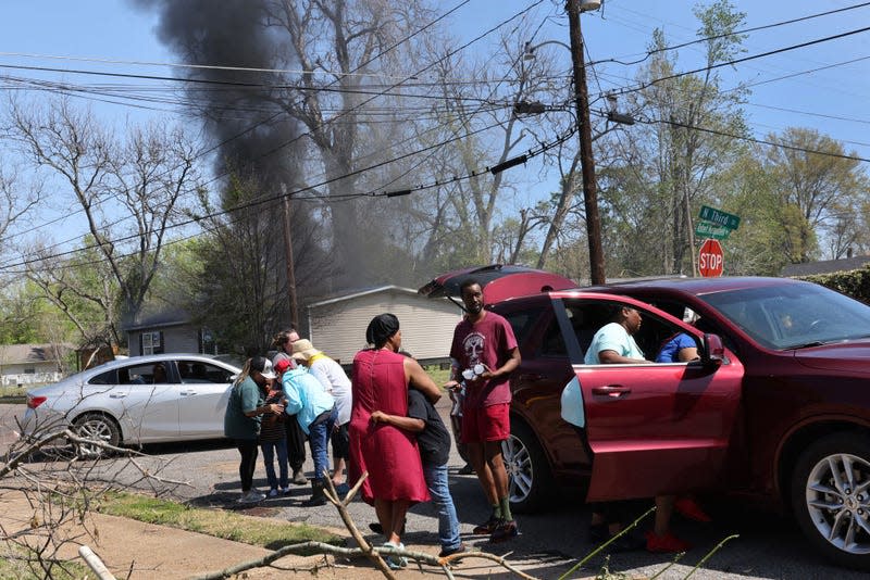 Family members are comforted after their home caught fire, which was reported to have been started by a generator used to supply the home with power after an EF-4 tornado knocked out power in Rolling Fork, Mississippi. 