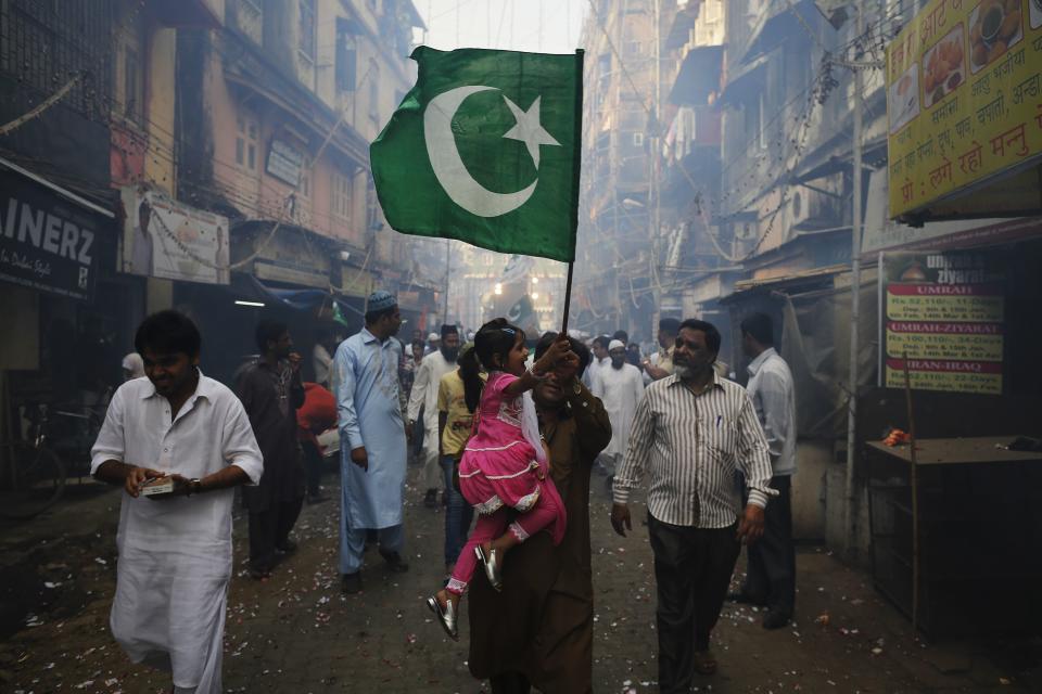 A man and his daughter wave an Islamic religious flag they participate in a procession to mark Eid-e-Milad-ul-Nabi, or birthday celebrations of Prophet Mohammad in Mumbai