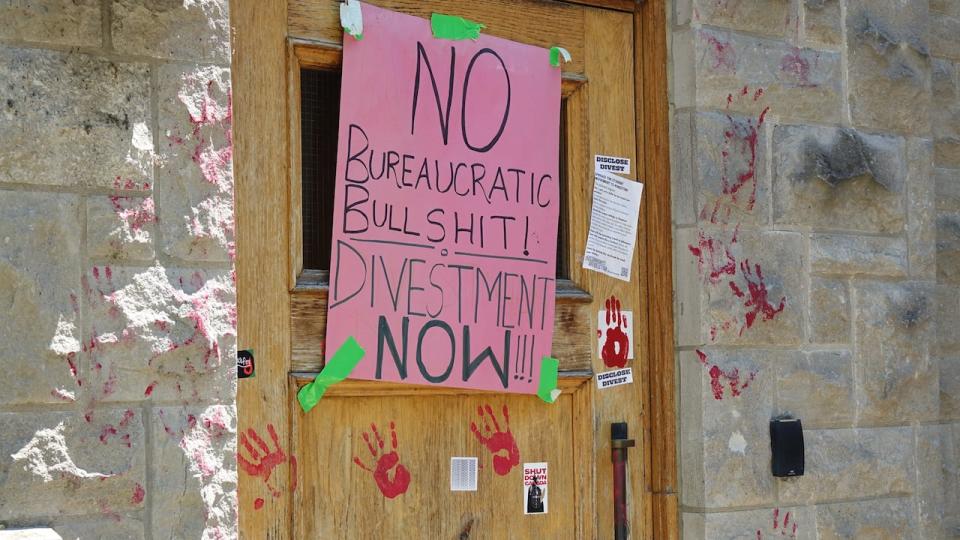 Protesters covered the walls of a courtyard at Queen's University with posters and paint calling for their six demands to be met.