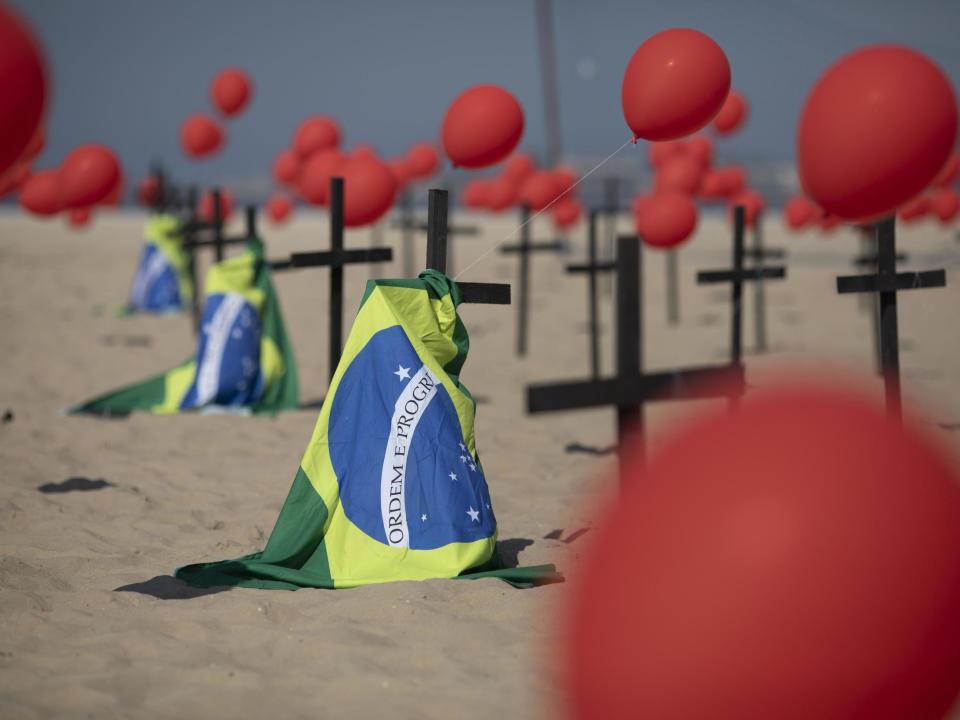 Crosses, red balloons and Brazilian nation flags are placed in the sand on Copacabana beach in a demonstration organised by Rio de Paz: AP Photo/Silvia Izquierdo