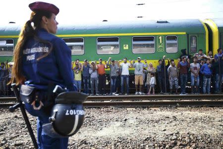 A police officer stands guard as migrants stage a protest in front of a train at Bicske railway station, Hungary, September 4, 2015. REUTERS/Leonhard Foeger