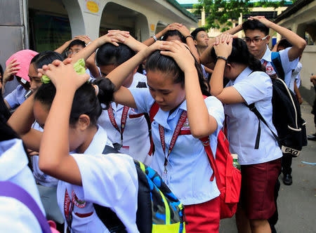 Students use their hands to cover their heads as they evacuate their school premises after an earthquake hit the northern island of Luzon and was felt in the Metro Manila, Philippines August 11, 2017. REUTERS/Romeo Ranoco