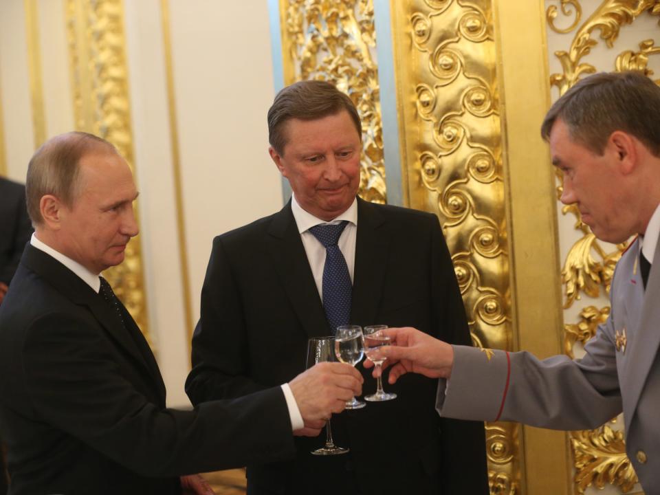 Russian President Vladimir Putin (L) toasts holding a glass of vodka with Deputy Defence Minister Valery Gerasimov (R) as Presidential Administration Chief of Staff Sergei Ivanov (C).