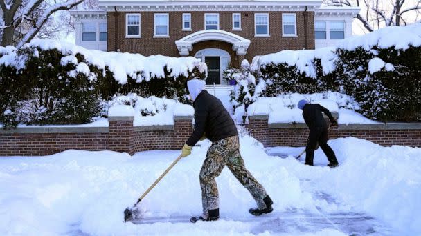 PHOTO: Kids shovel snow off a sidewalk and driveway Dec. 22, 2022, in Minneapolis. (Abbie Parr/AP)