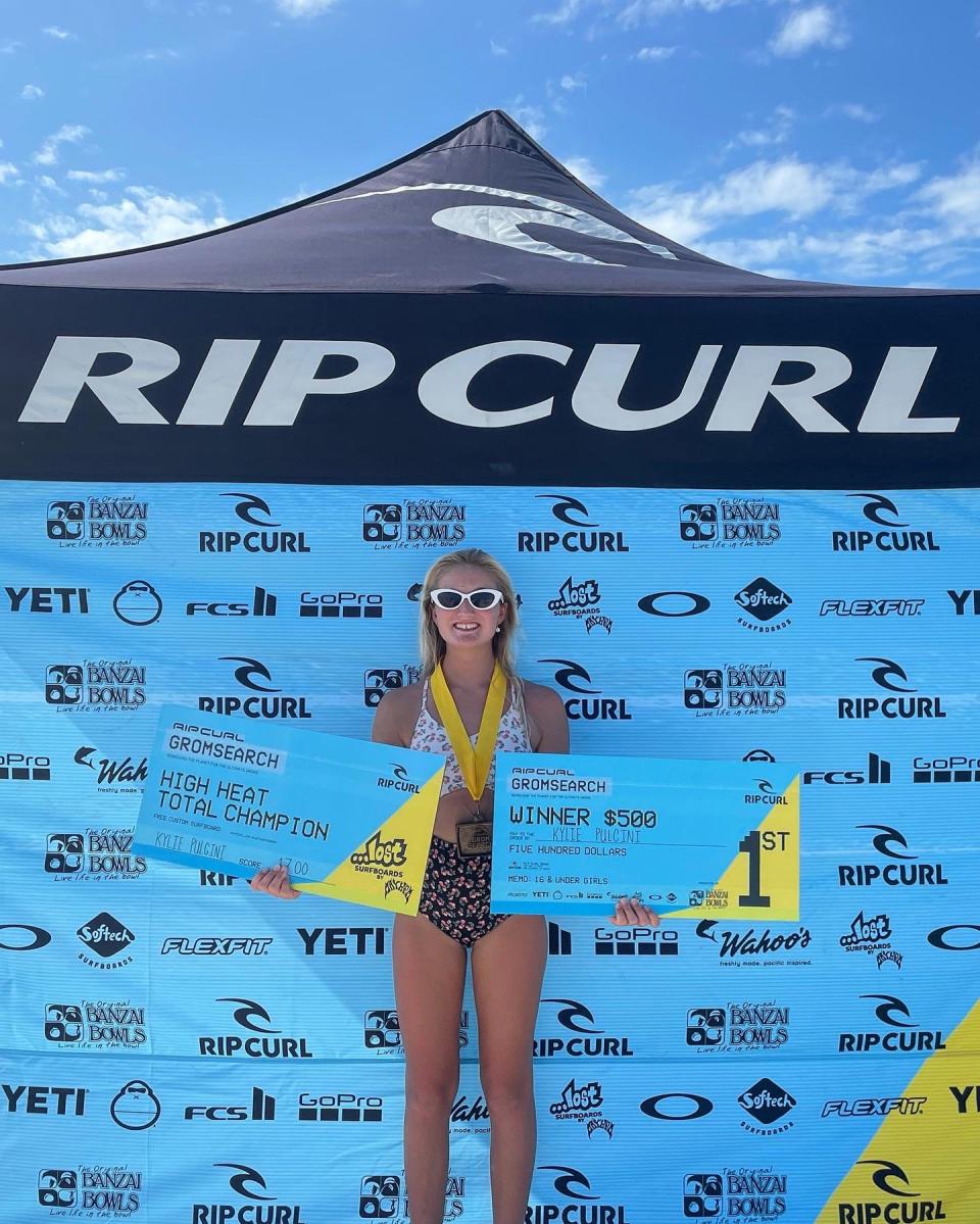 Kylie Pulcini, 14, shows off her two first-place checks after winning the prestigious Rip Curl Grom Search contest and posting the highest heat total among girls and boys.