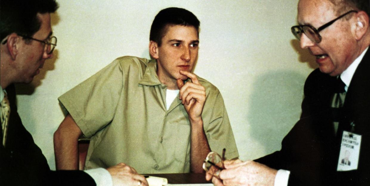 timothy mcveigh, wearing a tan prison jumpsuit, listening to two men in suits and glasses at a table