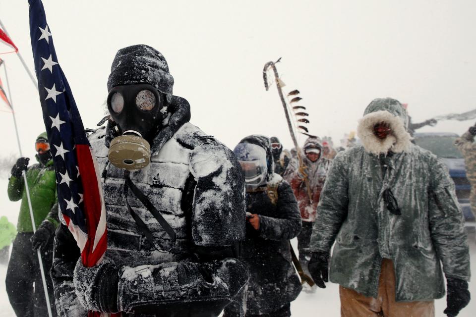 A man takes part in a march with veterans to Backwater Bridge just outside of the Oceti Sakowin Camp during a snow fall as 