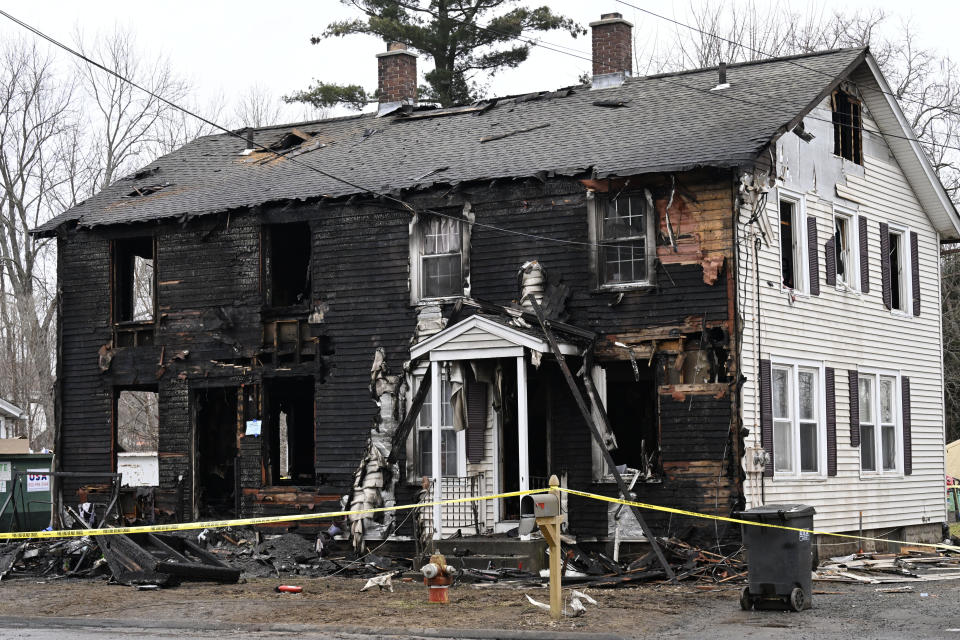 Charred siding and items are strewn about at a two-family home Wednesday, Jan. 3, 2024, in Somers, Conn., in the aftermath of a fatal fire. Four children died Tuesday night in a fire that broke out in the two-family home. The children, ages 5, 6, 8 and 12, were found inside the house where 11 people lived, fire and town officials said. (AP Photo/Jessica Hill)