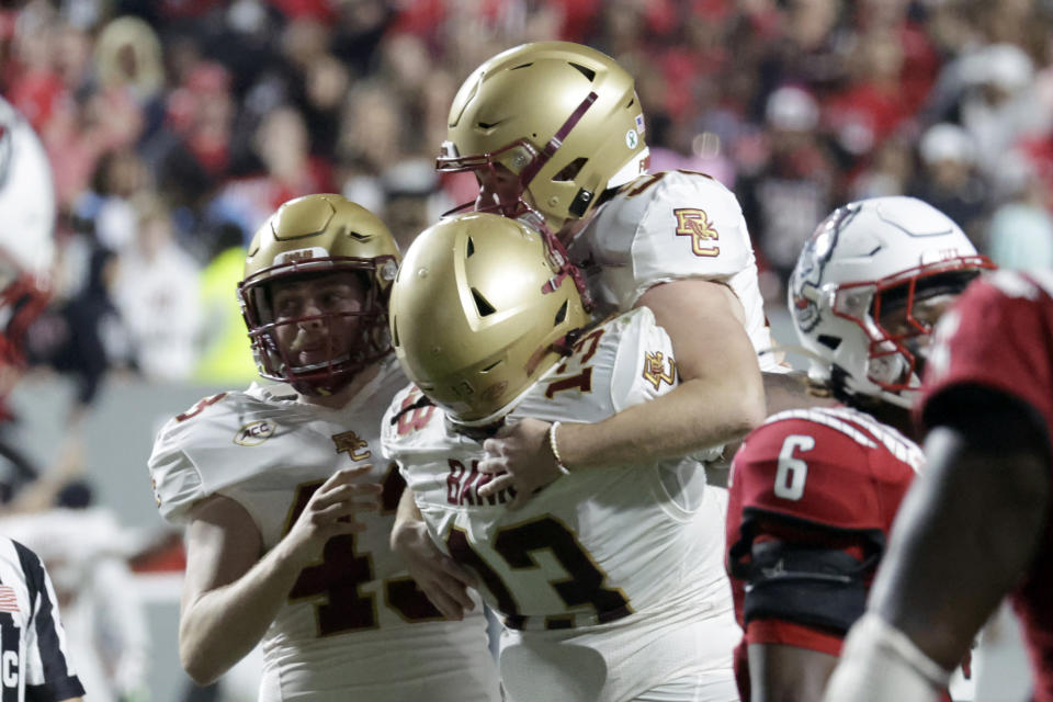 Boston College placekicker Connor Lytton, top, celebrates his kick for an extra point with defensive lineman Khris Banks (13) and punter Sam Candotti, left, after he scored against North Carolina State in the final moments of the second half of an NCAA college football game Saturday, Nov. 12, 2022, in Raleigh, N.C. (AP Photo/Chris Seward)