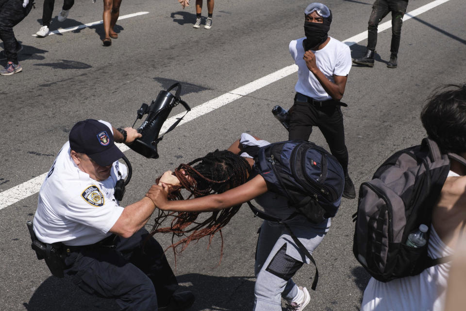 Black Lives Matter protesters scuffle with an NYPD officer on the Brooklyn Bridge in New York during a demonstration Wednesday, July 15, 2020. Several New York City police officers were attacked and injured during the protest, police said, and more than a dozen people were arrested. (AP Photo/Yuki Iwamura)