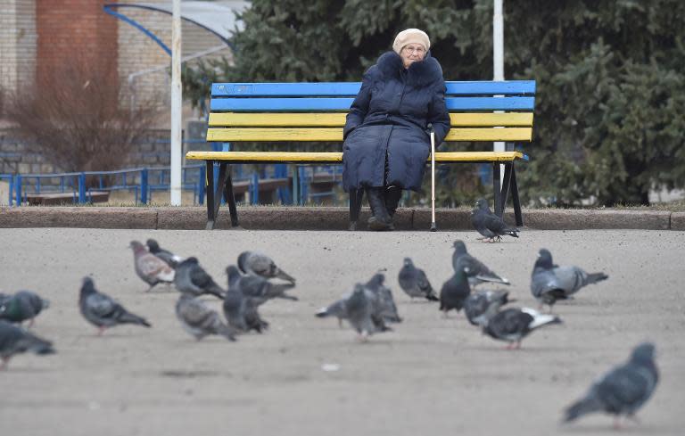 A woman sits on a bench painted in the colors of the Ukrainain flag in the eastern Ukrainian city of Slavyansk, Donetsk region, controlled by Ukrainian forces on March 12, 2015
