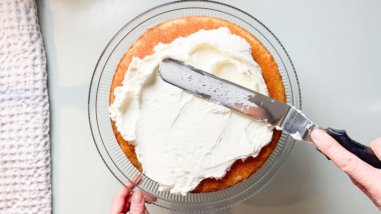 Spreading Swiss meringue buttercream on bright and sunny lemon lavender cake with offset spatula