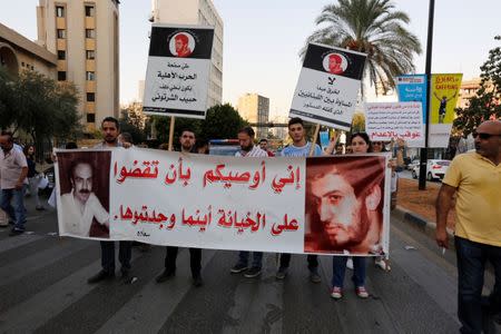 Supporters of the Syrian Socialist Nationalist Party (SSNP) carry a banner with pictures of Nabil al Alam (L) and Habib Shartouni (R) during a protest outside a court building in Beirut, Lebanon October 20, 2017. The biggest banner reads: "I advise you to judge treachery wherever you find it". REUTERS/Jamal Saidi