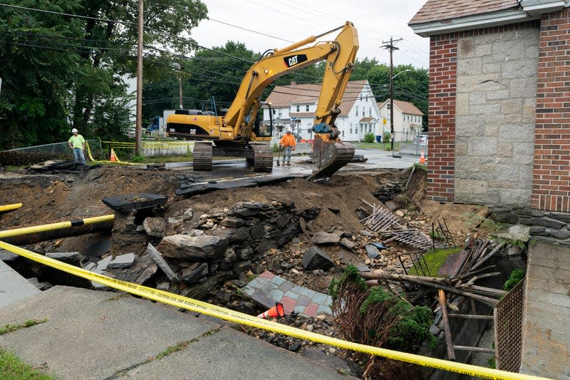A sidewalk is removed by an excavator in front of a home where the front yard and road were washed away by recent flooding, on September 13, 2023, in Leominster, Massachusetts. 