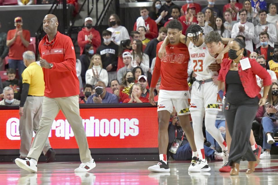 Maryland interim head coach Danny Manning, left, walks on the court as Ian Martinez (23) is helped off the court after an injury during an NCAA college basketball game against Northwestern in College Park, Md., Sunday, Dec. 5, 2021. (Amy Davis/The Baltimore Sun via AP)
