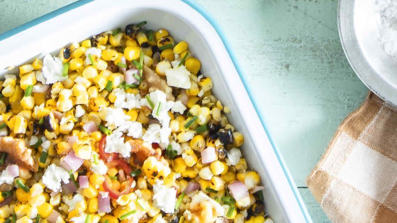 grilled corn salad in a white baking dish with crumbled feta on top