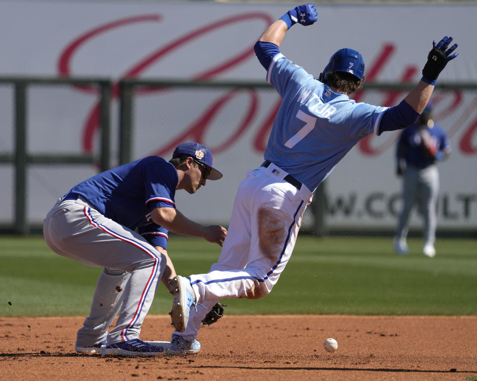 Kansas City Royals' Bobby Witt Jr. (7) beats the tag by Texas Rangers shortstop Corey Seager to steal first base during the first inning of a spring training baseball game Friday, Feb. 24, 2024, in Surprise, Ariz. (AP Photo/Charlie Riedel)