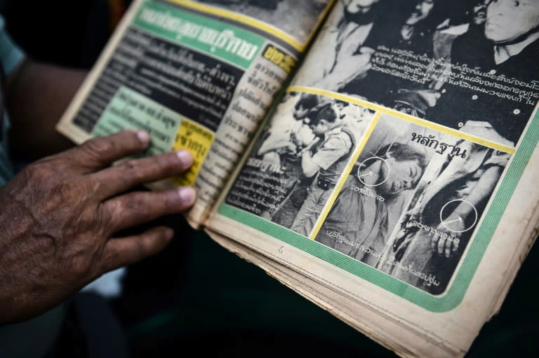 Chumpol Thummai holding a newspaper with a photograph of his left-wing activist brother after he was lynched by Thai royalists