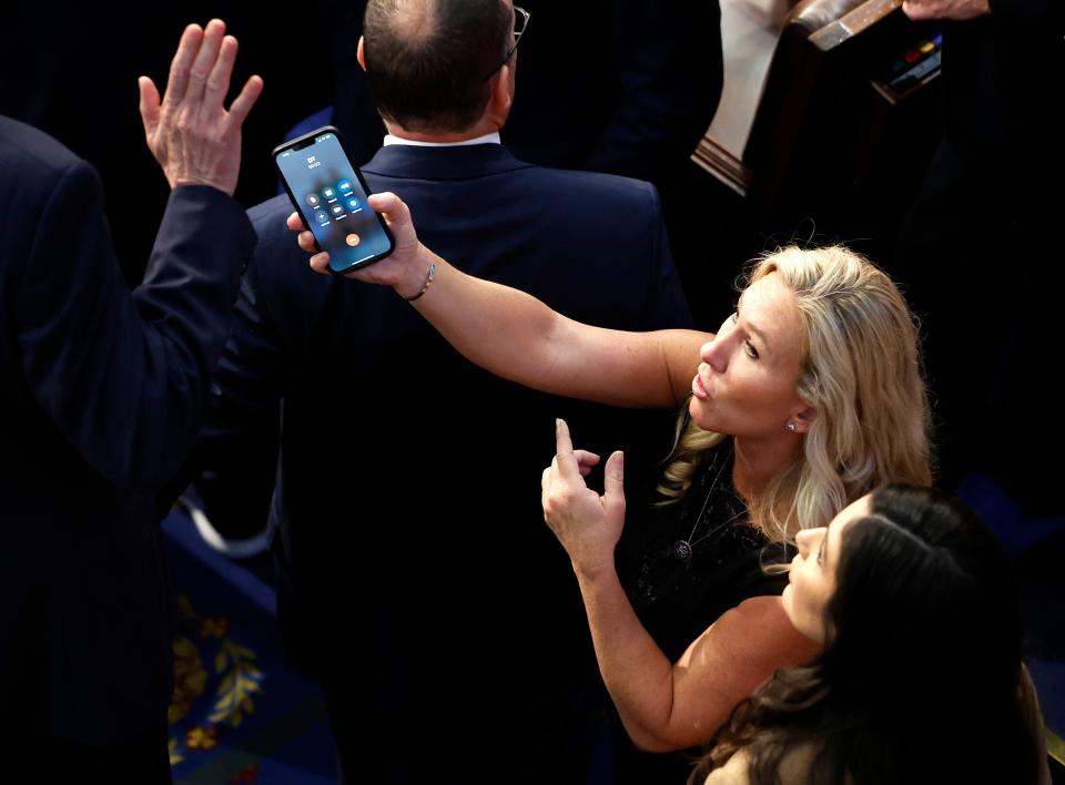 Rep.-elect Marjorie Taylor Greene (R-GA) offers a phone to Rep.-elect Matt Rosendale (R-MT) in the House Chamber during the fourth day of voting for Speaker of the House at the U.S. Capitol Building on January 06, 2023 in Washington, DC.