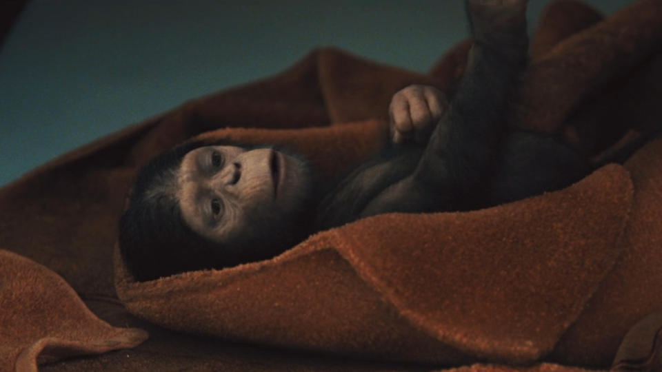 Baby Caesar lies on the floor swaddled in a blanket in Rise of the Planet of the Apes.