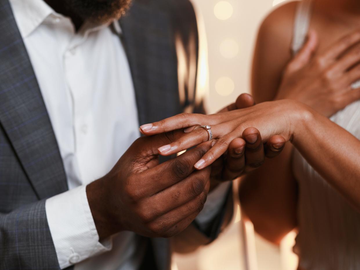 Man putting wedding ring on wife's finger.