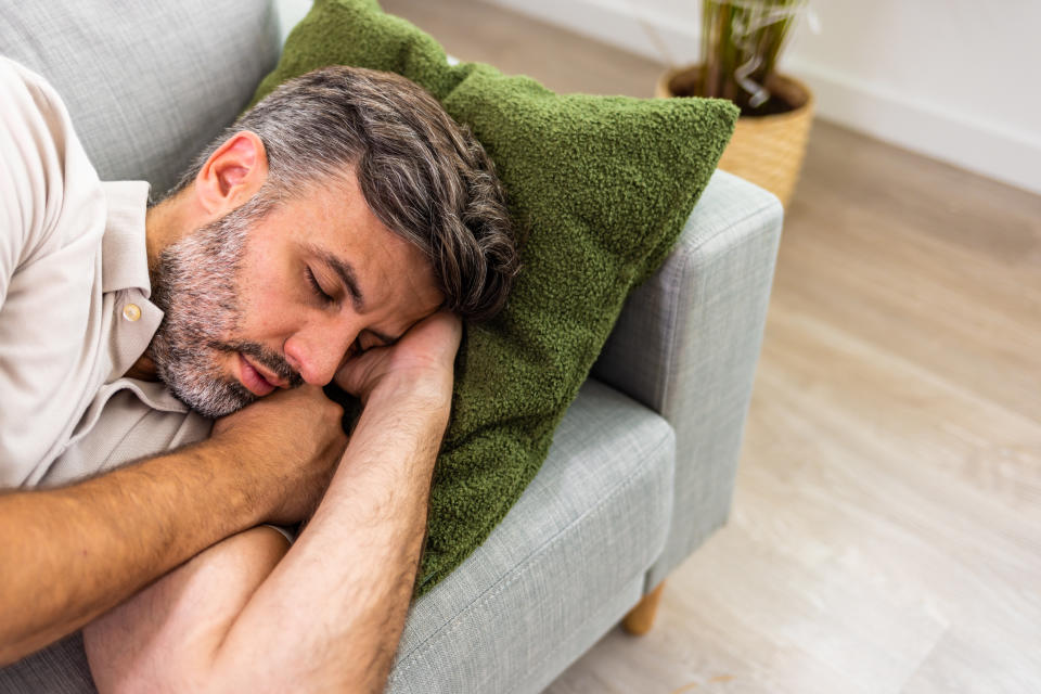 Exhausted young man came home after work flopped down on sofa