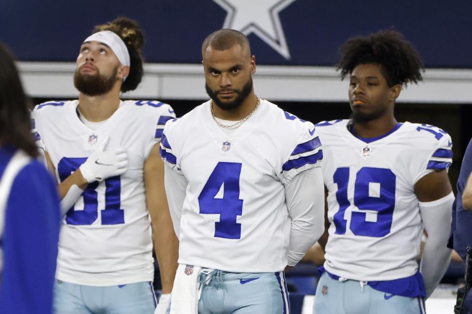 Dallas Cowboys quarterback Dak Prescott (4) and wide receiver Dontario Drummond (19) stand during the playing of the national anthem before the first half of a preseason NFL football game against the Seattle Seahawks in Arlington, Texas, Friday, Aug. 26, 2022. (AP Photo/Michael Ainsworth)