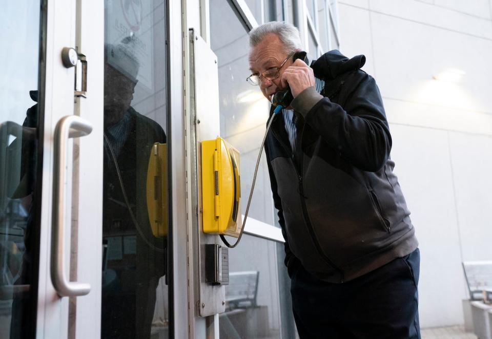 MPP Randy Hillier uses a phone to call and announce his arrival at a locked door as he attempts to turn himself in at the Ottawa Police Services headquarters March 28, 2022. Police announced nine charges against him soon after.