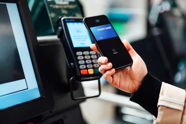 Close-up shot of a woman using contactless payment via smartphone to pay for her shopping at self-checkout counter in a store (Photo: Oscar Wong via Getty Images)