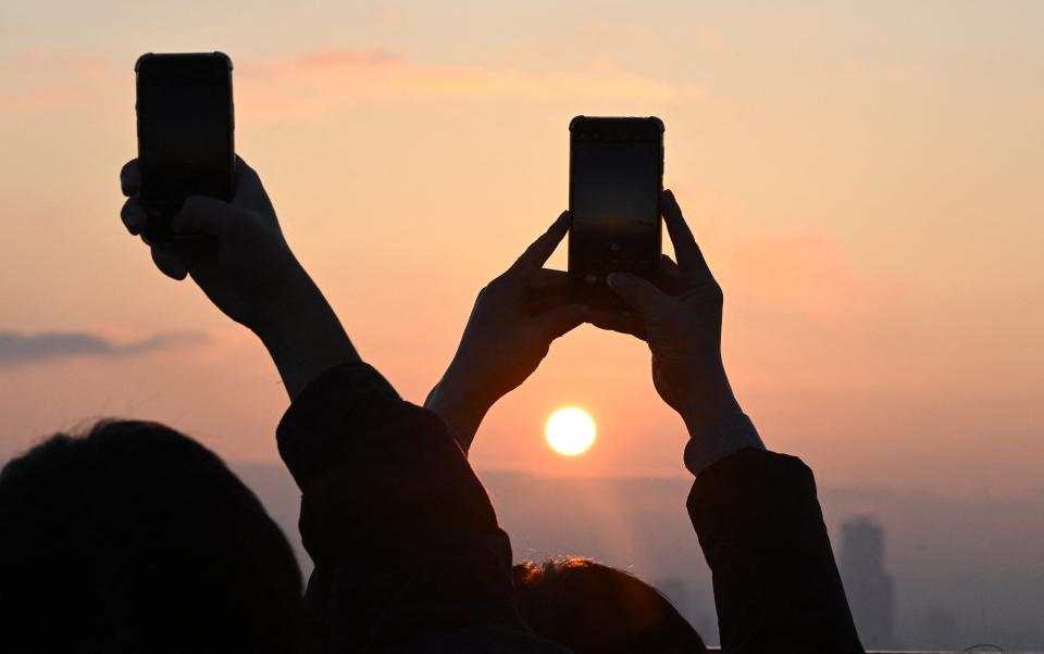 People take pictures as they observe the last sunset of the year on a viewing deck at Namsan tower in Seoul (AFP via Getty Images)