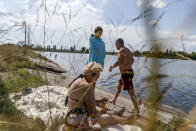 Anastasiia Aleksandrova, 12, center, stands along the water's edge for a picnic with her grandparents, Olena, left, and Andreii, at a lake in Sloviansk, Donetsk region, eastern Ukraine, Monday, Aug. 8, 2022. "All our plans for summer are ruined but we are trying hard to make her life as colorful as possible," said Olena. "She is always with us, because you never know when and where there might be bombings. War does not bring happiness to anybody." (AP Photo/David Goldman)