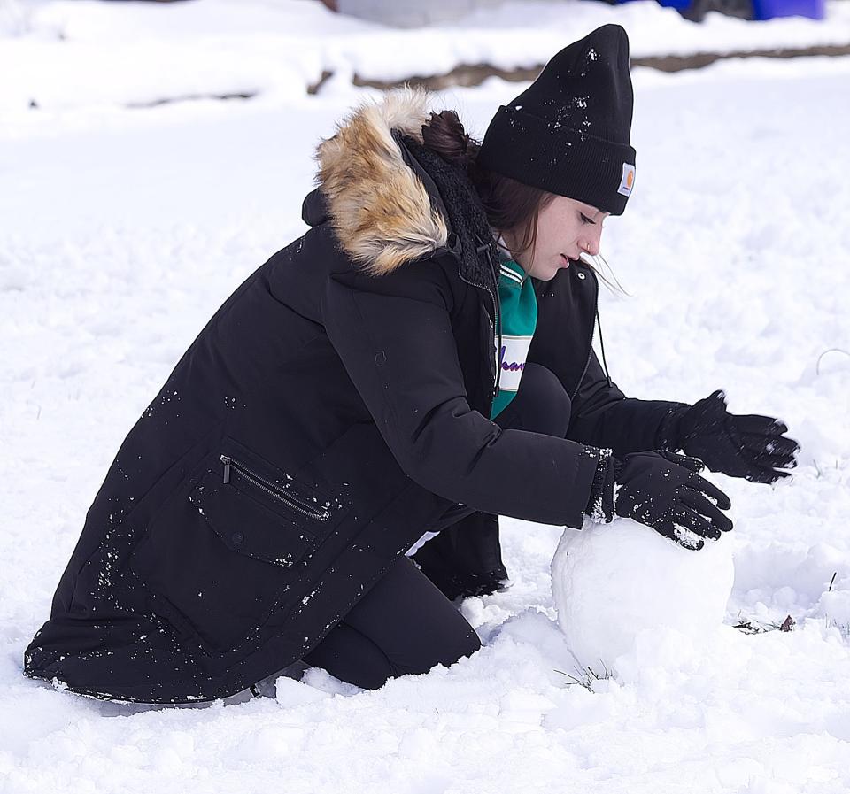 Kent State Univesity student Emily Pace works on the beginnings of a snowman on East College Avenue on in Kent.