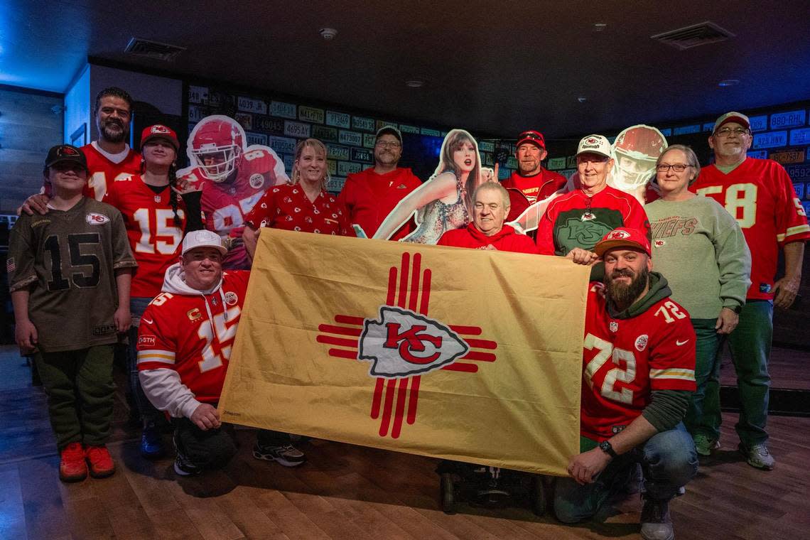 Members of the Facebook group Chiefs Kingdom New Mexico chapter pose with life-size cutouts of Kansas City Chiefs tight end Travis Kelce, pop star Taylor Swift and quarterback Patrick Mahomes at the Local Brew House in Albuquerque, N.M., on Wednesday, Feb. 7, 2024. They proudly display a customized New Mexico Chiefs-themed flag, highlighting their passion for the team.