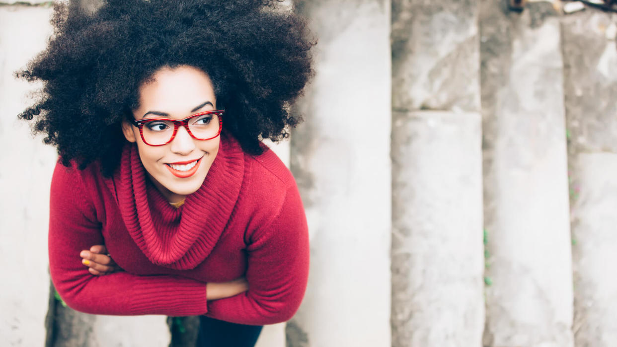 Portrait of smiling young woman standing arm crossed on staircase.