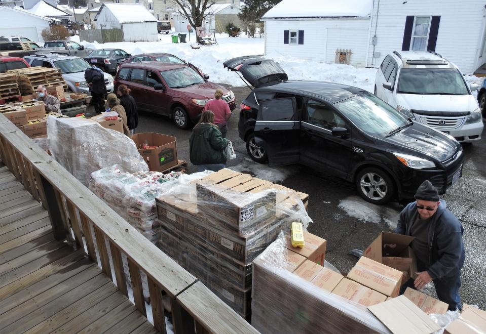 Individuals go through boxes containing produce outside Upper Room Assembly and Worship Center during its most recent food pantry day.