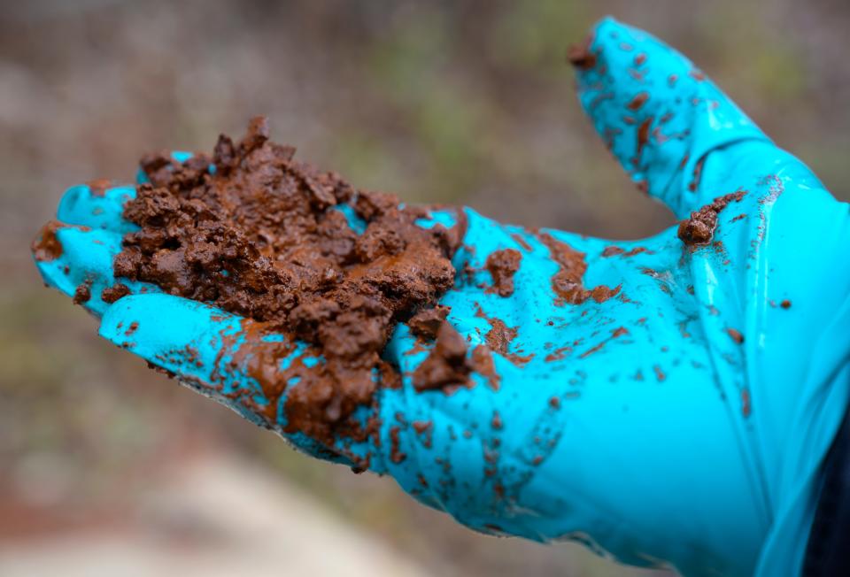 Ohio University art professor John Sabraw holds up a handful of earth which has been permeated by iron oxide and other toxins from an old mine seep in Athens County. He is working with a chemistry professor and Rural Action, Inc., to build a water treatment plant nearby which will remove the pollution from the water, creating pigment for paint with the byproduct.