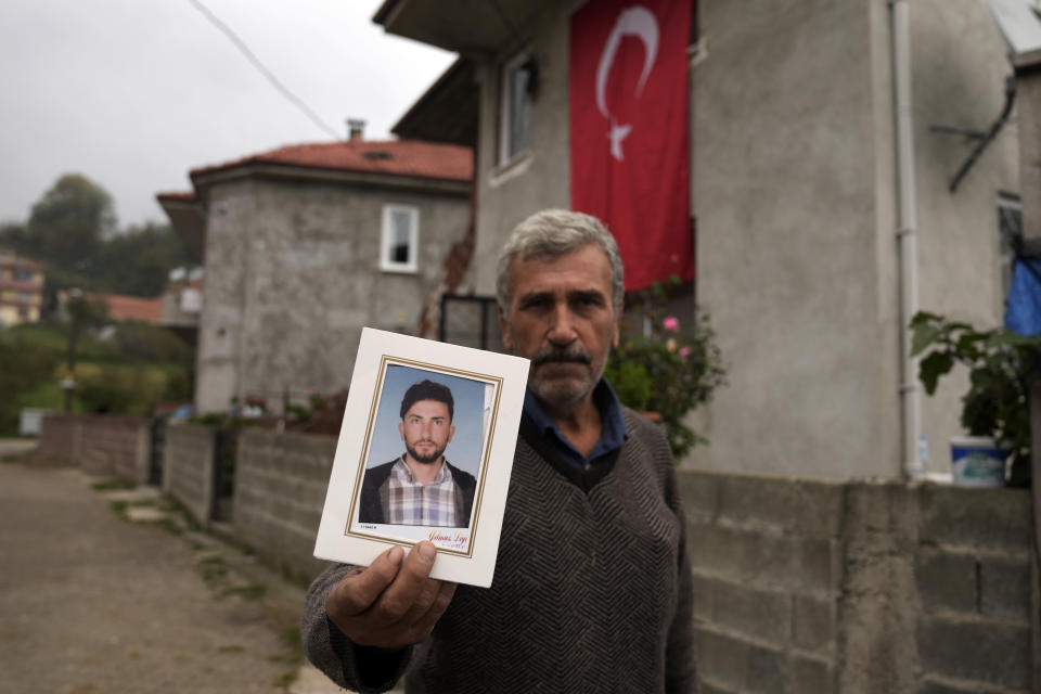 Recep Ayvaz, 62, shows a picture of his son, Selcuk Ayvaz, 33, one of the miners killed in a coal mine explosion, in front of his house in Amasra, in the Black Sea coastal province of Bartin, Turkey, Sunday, Oct. 16, 2022. (AP Photo/Khalil Hamra)