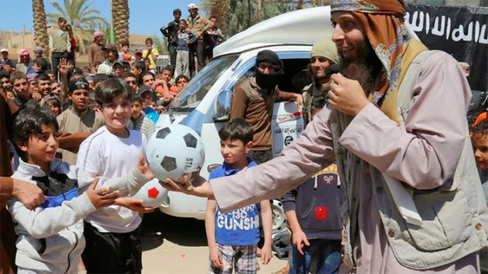 Ball is given to a boy, left, during a street preaching event in Tel Abyad in Raqqa province, northeast Syria. IS extremists have made it a priority to mold children under their rule into a new generation of militants, luring them into becoming fighters, suicide bombers and executioners. Photo: AP