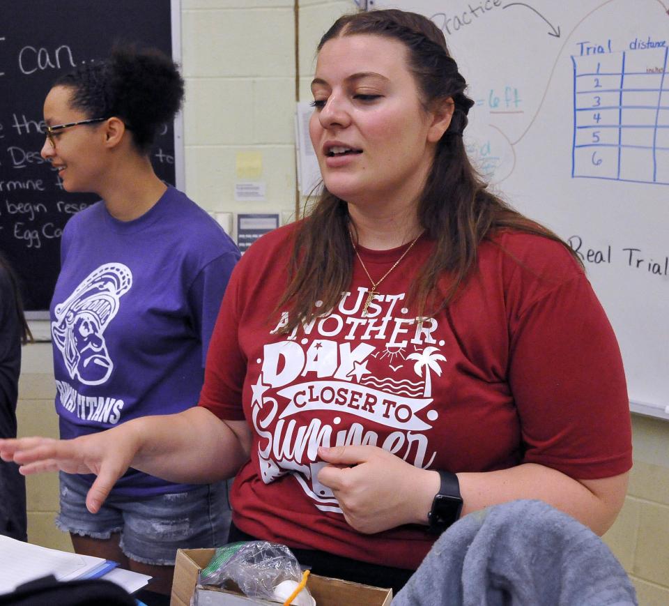 Co-teacher Emily Rolince tells how teams used play money to buy car constructions parts from a "store" so the cars would be more equal for the testing.