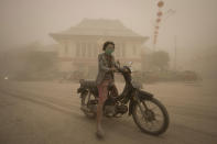 A women rides a motor bike on a street covered with volcanic ash from an eruption of Mount Kelud, in Solo, Indonesia, Friday, Feb. 14, 2014. A major volcanic eruption in Indonesia blasted clouds of ash and debris 18 kilometers (12 miles) into the air on Friday, forcing authorities to close six airports, cancel flights elsewhere in Southeast Asia and evacuate more than 100,000 people from the mountain. (AP Photo/ Hafidz Novalsyah)