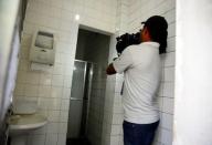 A television cameraman films in the men's bathroom at the gasoline station where U.S. swimmers Ryan Lochte, Jimmy Feigen, Jack Conger and Gunnar Bentz were accused by staff of having caused damage, in Rio de Janeiro. REUTERS/Nacho Doce